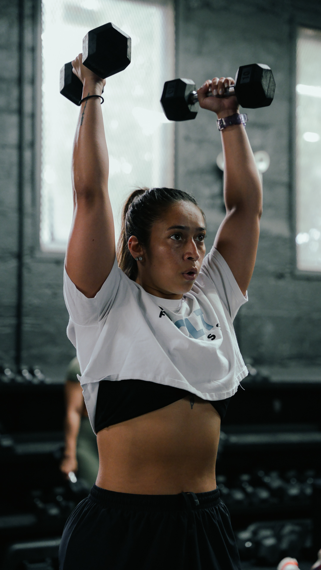 Athlete overhead pressing dumbbells at BOLT Fitness Brooklyn