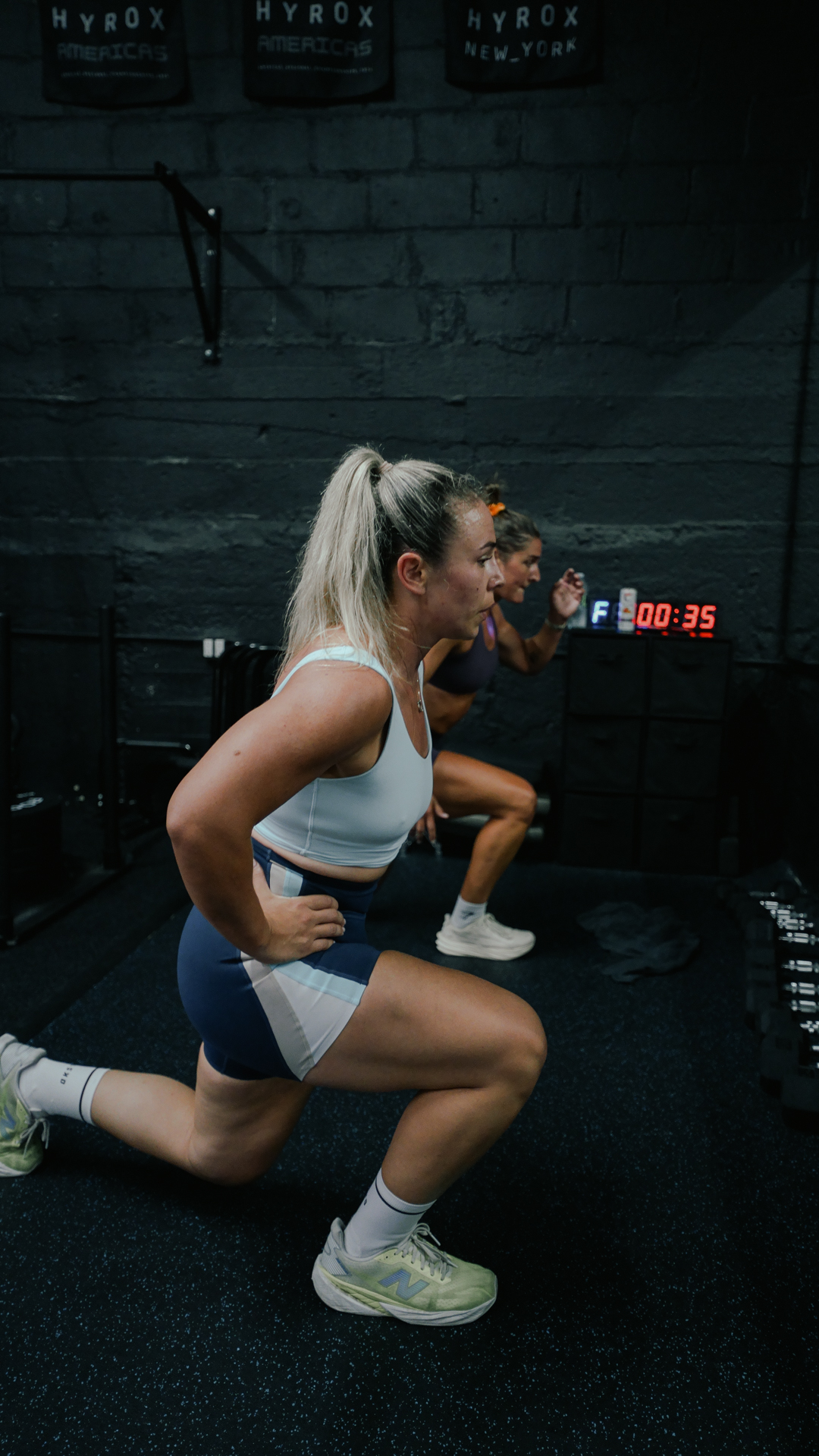 Sandbag lunges under HYROX banners at BOLT Fitness